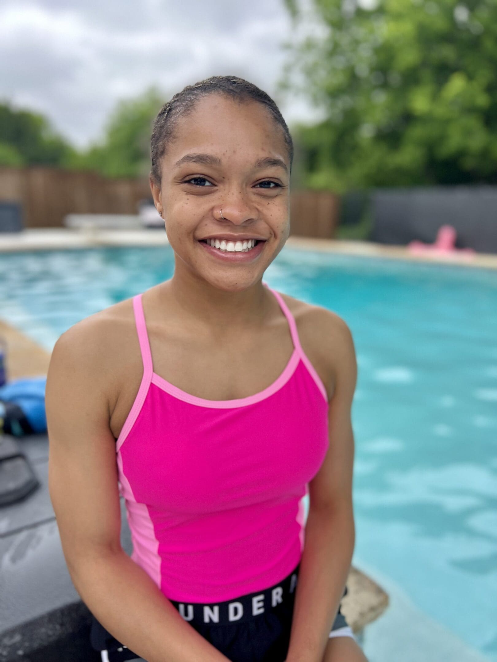 Smiling woman in pink swimsuit by pool